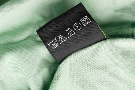 Care instructions clothing label on green textile background