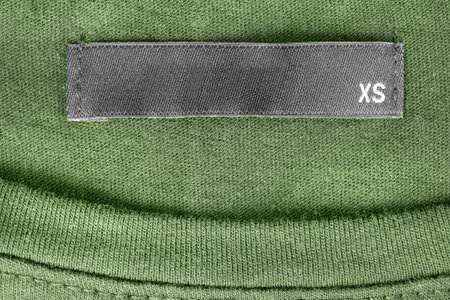 Size XS clothing label on green knit background
