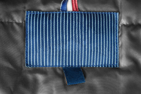 Blank blue striped clothing label on textile background closeup