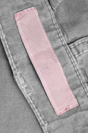 Blank pink clothing label on gray denim background closeupの写真素材