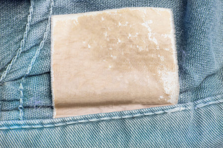 Blank clothing label on blue cotton background closeup