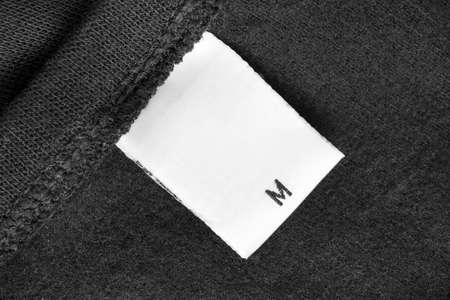 Size M clothing label on black textile background closeupの写真素材