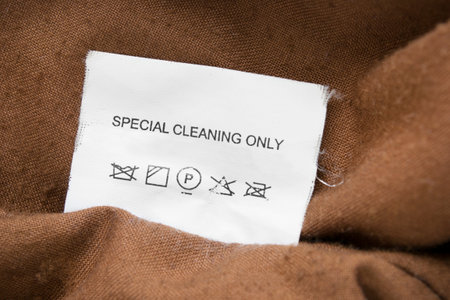 Clothing label says special cleaning only on brown textile background closeupの写真素材