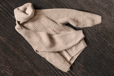 Beige wool turtle neck sweater on dark brown wooden backgroundの写真素材