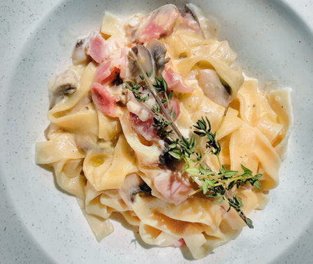 Italian fettuccine with ham and mushrooms on a dish closeupの写真素材