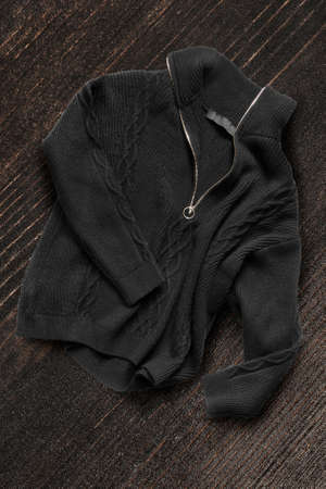 Black knit zip neck jumper on dark brown wood backgroundの写真素材