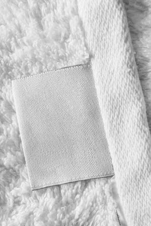 Blank white clothing label on white textile background closeupの写真素材