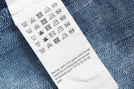 Care instructions clothing label on blue denim background closeup