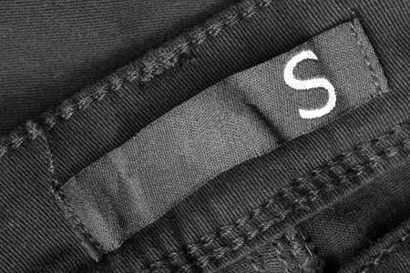 Size S clothing label on black textile background closeupの写真素材