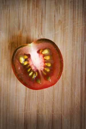 Half of fresh brown cherry tomato on wood cutting board backgroundの写真素材
