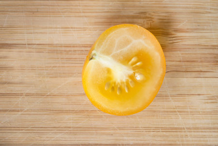 Half of yellow cherry tomato on cutting boardの写真素材
