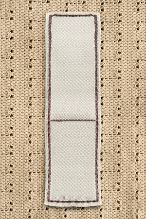 Blank textile clothing label on yellow knit background