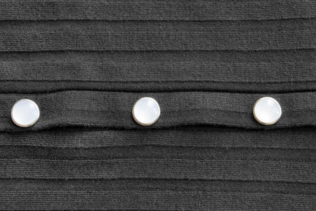 White clothing buttons on black knit textile background closeupの写真素材