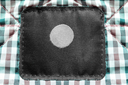 Blank clothing label on plaid textile background closeup