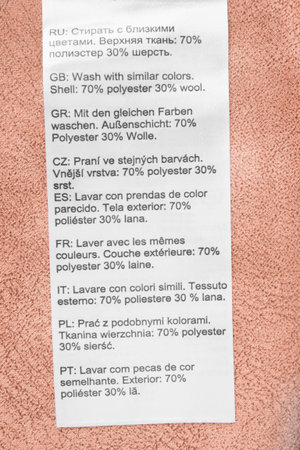 Composition and care clothing label in different languages on pink fabric