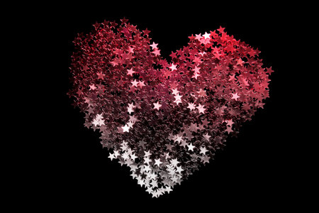 Pink and silver glitter in the shape of a heart on black backgroundの写真素材