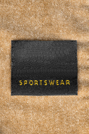 Clothing label saysn sportswear on yellow knit background