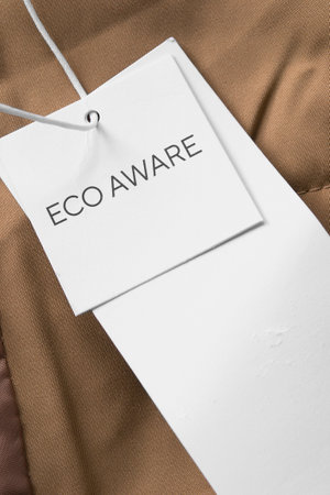 White paper clothing label says eco aware on brown fabricの写真素材