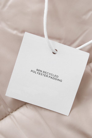 Clothing label says 98% recycled polyester padding on beige fabric