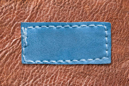 Blue blank patch stitched on brown leather backgroundの写真素材
