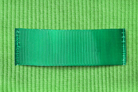 Green blank clothing label sewn on green knit background closeupの写真素材