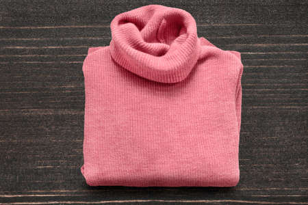 Folded pink wool sweater on dark wood backgroundの写真素材