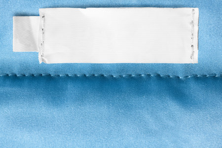Empty clothing label on blue stitched fabric background