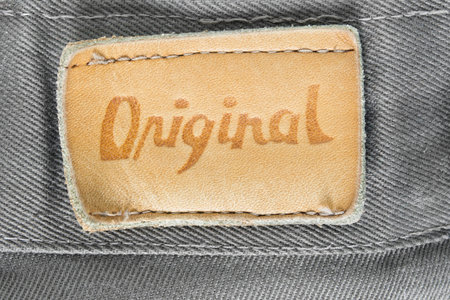 Clothing label says original on gray denim background closeup