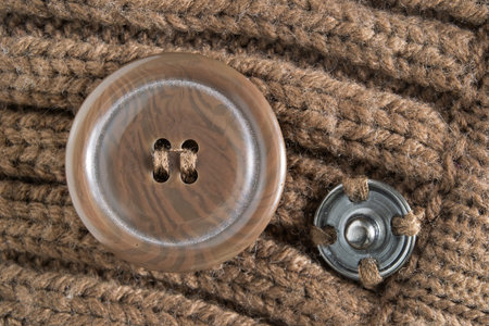 Button and clasp button sewn on brown knit fabric closeup
