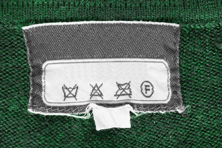 Care instructions clothing label on green knit background