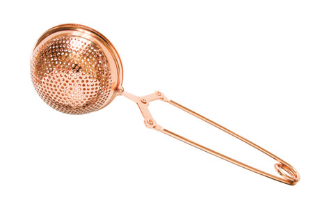 Golden colored ball tea strainer on white background