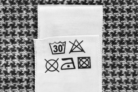 Care instructions clothing label on black and white knit background