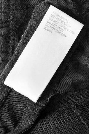 Care instructions clothing label on black fabric background