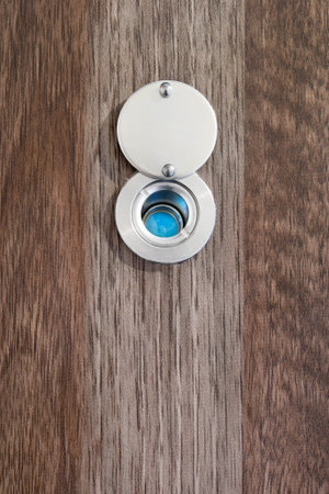 Eye peephole in dark brown wooden door