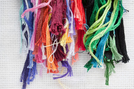 Colorful embroidery threads on white canvas background