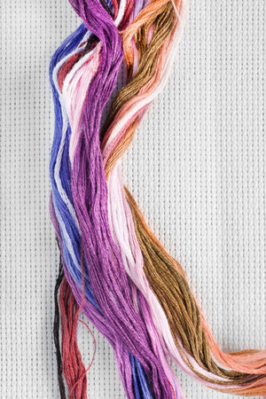 Colorful silk embroidery thread on white canvas background