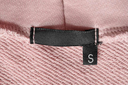 Size S clothing label on pink back side fabric as a backgroundの写真素材