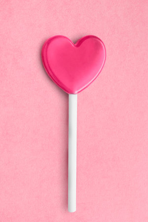 Pink heart shaped lollipop on pink backgroundの写真素材