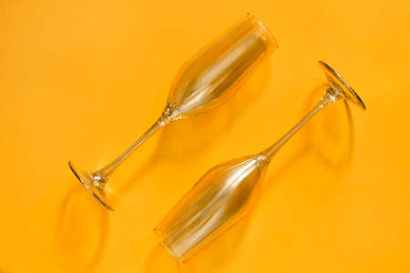 Two golden clean champagne glasses on yellow backgroundの写真素材