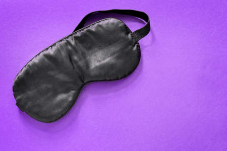 Black silk sleeping mask on purple backgroundの写真素材