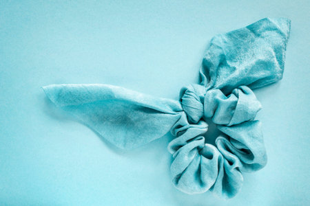 Blue silk scrunchy with a bow on blue background