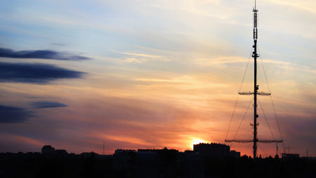 Black silhouettes of town and antenna mast on beautiful sunset sky
