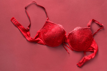 Red lacy unfastened push up bra on red background