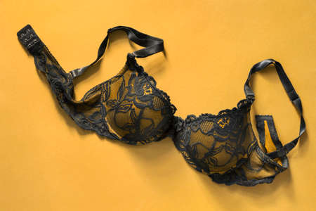 Unfastened black and yellow lacy push up bra on yellow backgroundの写真素材