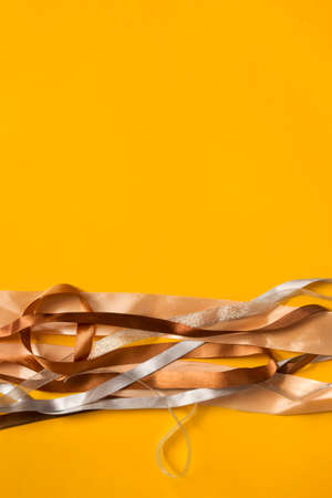 Brown and silver wrapping ribbons on yellow backgroundの写真素材