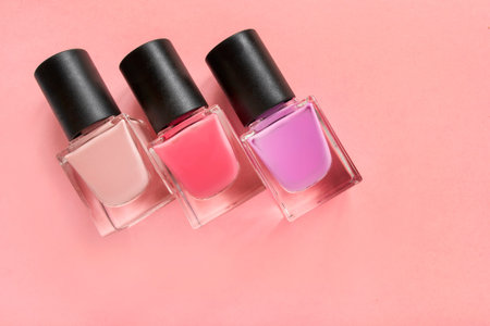Beige and pink colors nail polish jars on pink backgroundの写真素材