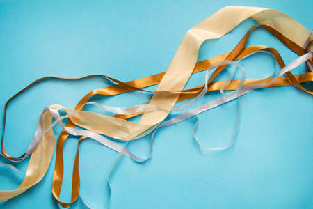 Golden and silver wrapping ribbons on blue color backgroundの写真素材