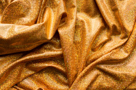 Golden holographic draped fabric closeup as a backgroundの写真素材
