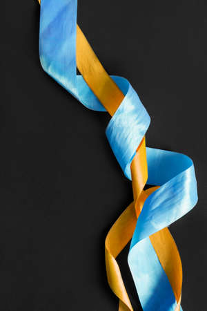 Blue and yellow ribbons closeup on black backgroundの写真素材