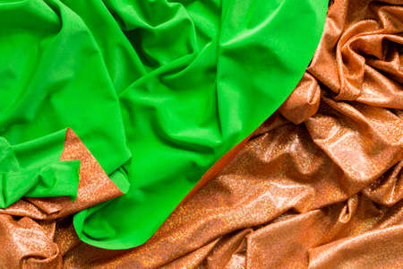 Draped two sided green and golden fabric as a backgroundの写真素材